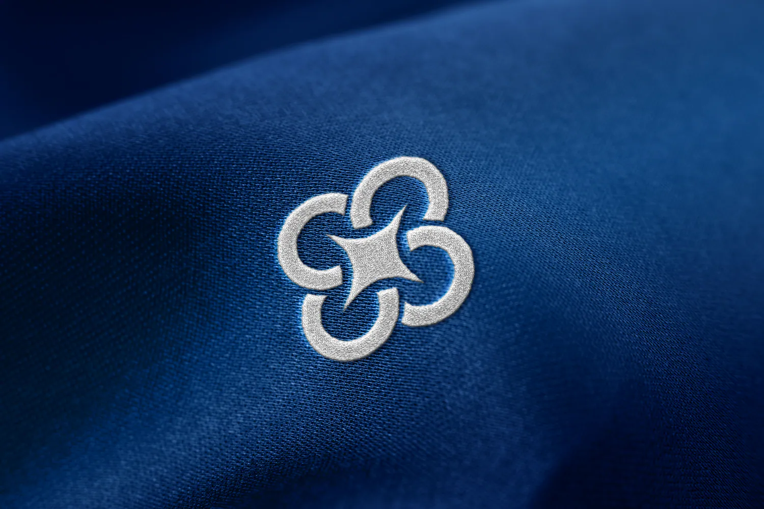 Embroidered Syntra symbol on deep blue fabric